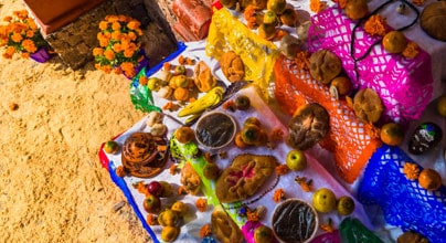 Ofrenda del Día de Muertos con alimentos flores y veladoras en medio de una casa en México