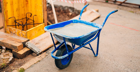 Carretilla azul cargando con mezcla de cemento en construcción