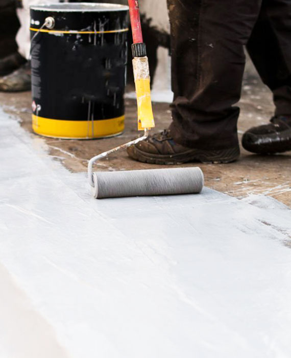 Persona aplicando impermeabilizante acrílico sobre el techo de una vivienda