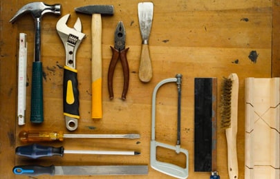 Herramientas de herrería colocadas en la mesa de un taller junto a una máquina para soldar