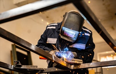 Herrero llevando a cabo una soldadura de perfiles en su taller de herrería