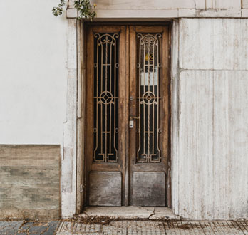 Protecciones de herrería instaladas sobre los vidrios de una puerta de madera antigua