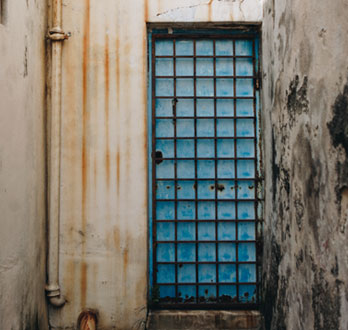 Puerta de color azul equipada con protección de herrería cuadriculada con una capa de óxido en su superficie