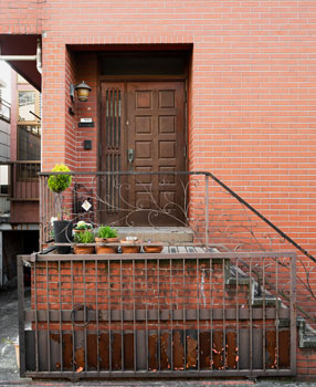 Puerta de herrería en exterior en la parte alta de unas escaleras que vienen de la calle