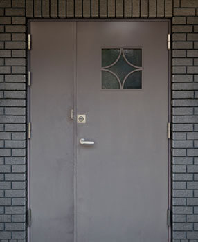 Puerta de herrería para entrada principal con diseño de doble hoja desigual y ventana