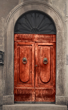 Puerta de madera con arco superior trabajado en herrería y vidrio