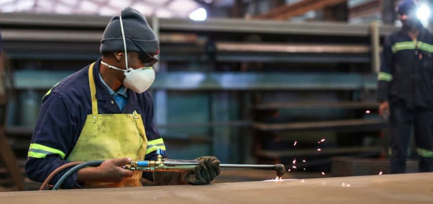 Empleado de planta de reciclaje equipado efectuando la técnica oxicorte en una superficie metálica