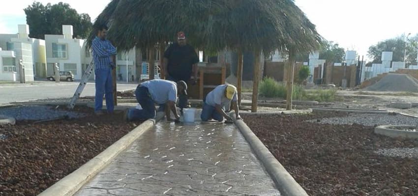 Trabajadores elaborando sendero de concreto estampado en área común de fraccionamiento